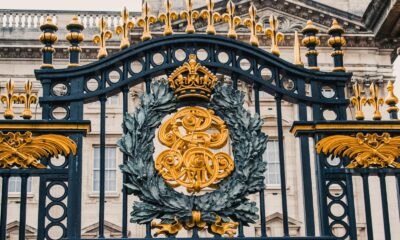 Detailed view of the ornate gold and black iron gate at Buckingham Palace, London.