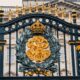 Detailed view of the ornate gold and black iron gate at Buckingham Palace, London.