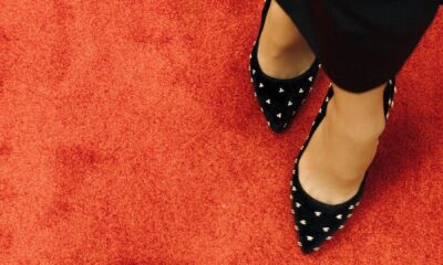 Black high heel shoes with studded design on vibrant red carpet. Fashion statement.