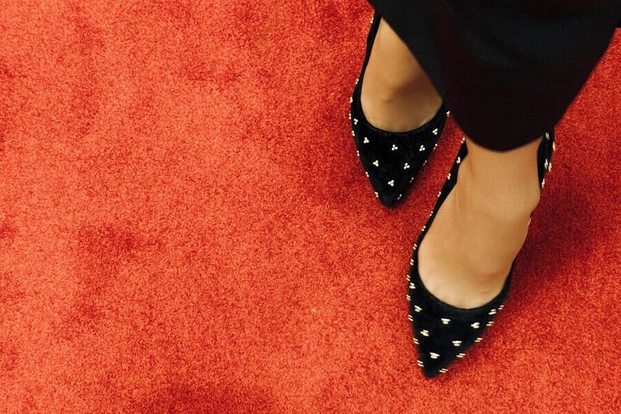 Black high heel shoes with studded design on vibrant red carpet. Fashion statement.
