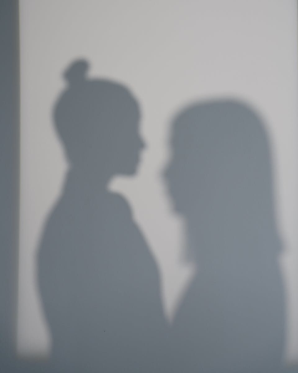 Two women's shadows cast on a wall creating an artistic silhouette effect.