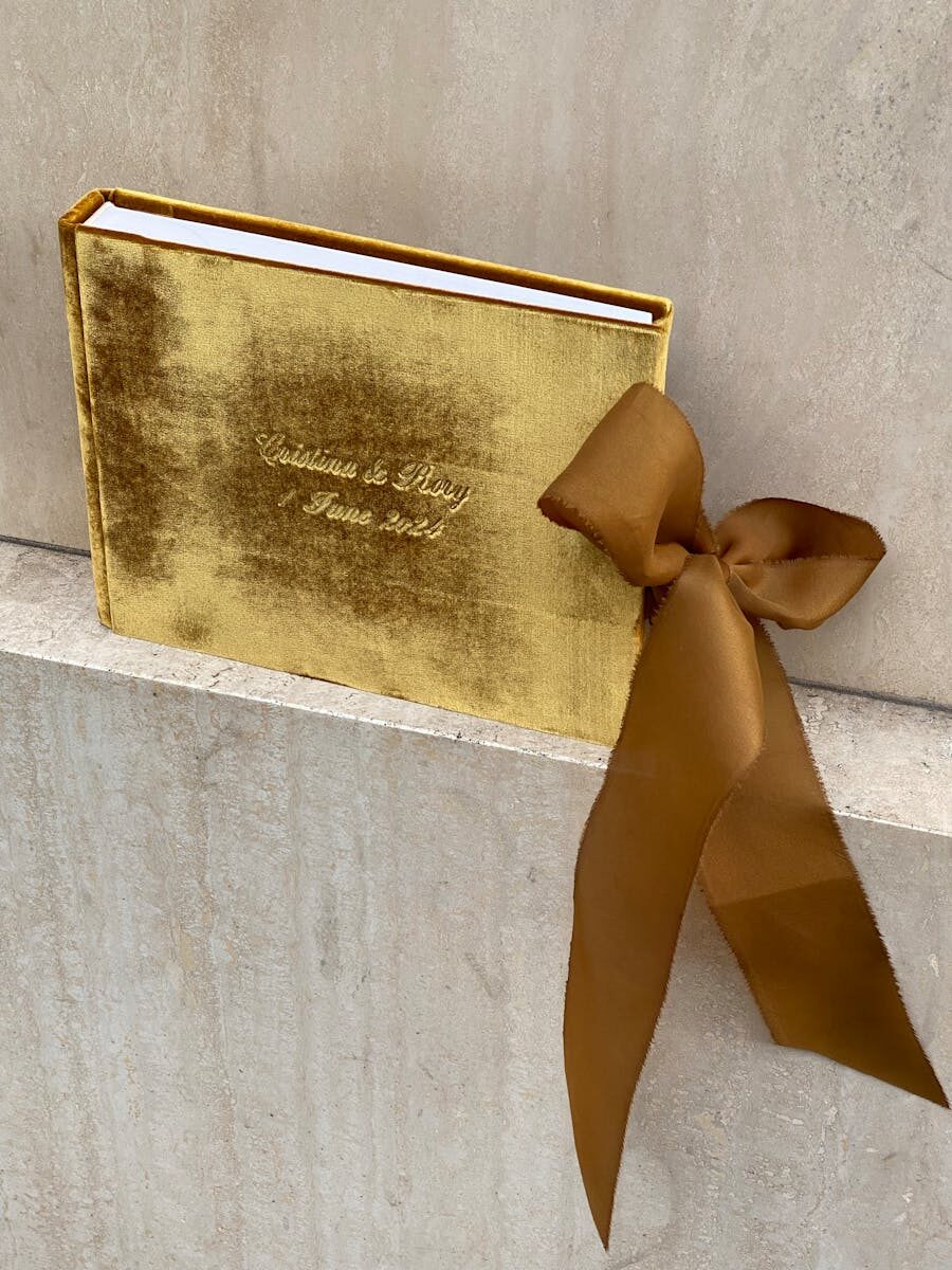 A luxurious gold velvet-covered book tied with an elegant ribbon, perfect for gifts and special occasions.