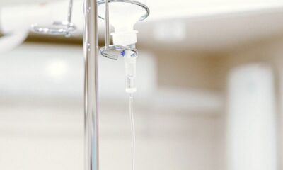 Close-up of an IV drip in a sterile hospital setting with background medical equipment.